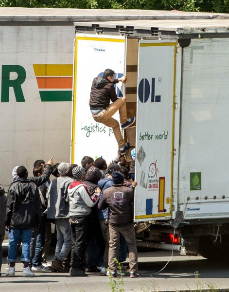 Göçmenler 23 Haziran 2015 tarihinde Eurotunnel'e giden A16 karayolu üzerinde bir kamyonun arkasında tırmanmaya çalışıyorlar