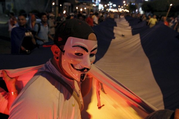 A demonstrator, wearing a Guy Fawkes mask, takes part in a march to demand the resignation of Honduras' President Juan Orlando Hernandez along the streets of Tegucigalpa