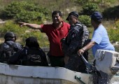 Miguel Angel Jimenez (in red), leader of the community police of Guerrero State (UPOEG), speaks with a federal police on a boat as they seek for the 43 Ayotzinapa students' missing, in Acatlan, in the southwestern state of Guerrero, October 30, 2014. Jimenez, who headed the search of the 43 missing students with their relatives, was killed on Saturday inside a taxi in Xaltianguis in the state of Guerrero, according local media. Picture taken, October 30, 2014. REUTERS/Henry Romero - RTX1NNYL
