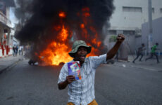 A protester kneels in front of a burning barricade with a copy of the Haitian Constitution during a demonstration demanding the resignation of President Jovenel Moise, in Port-au-Prince, Haiti, Friday, Jan. 15, 2021. Moise has one more year in power, but a growing groundswell of opposition is organizing protests and demanding he resign next month amid spiraling crime, a crumbling economy and approval of what critics say are illegal presidential decrees and unconstitutional moves, worrying many that Moïse is amassing too much power as he enters his second year of rule by decree. (AP Photo / Joseph Odelyn)