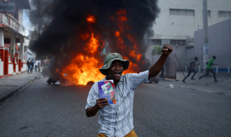 A protester kneels in front of a burning barricade with a copy of the Haitian Constitution during a demonstration demanding the resignation of President Jovenel Moise, in Port-au-Prince, Haiti, Friday, Jan. 15, 2021. Moise has one more year in power, but a growing groundswell of opposition is organizing protests and demanding he resign next month amid spiraling crime, a crumbling economy and approval of what critics say are illegal presidential decrees and unconstitutional moves, worrying many that Moïse is amassing too much power as he enters his second year of rule by decree. (AP Photo / Joseph Odelyn)